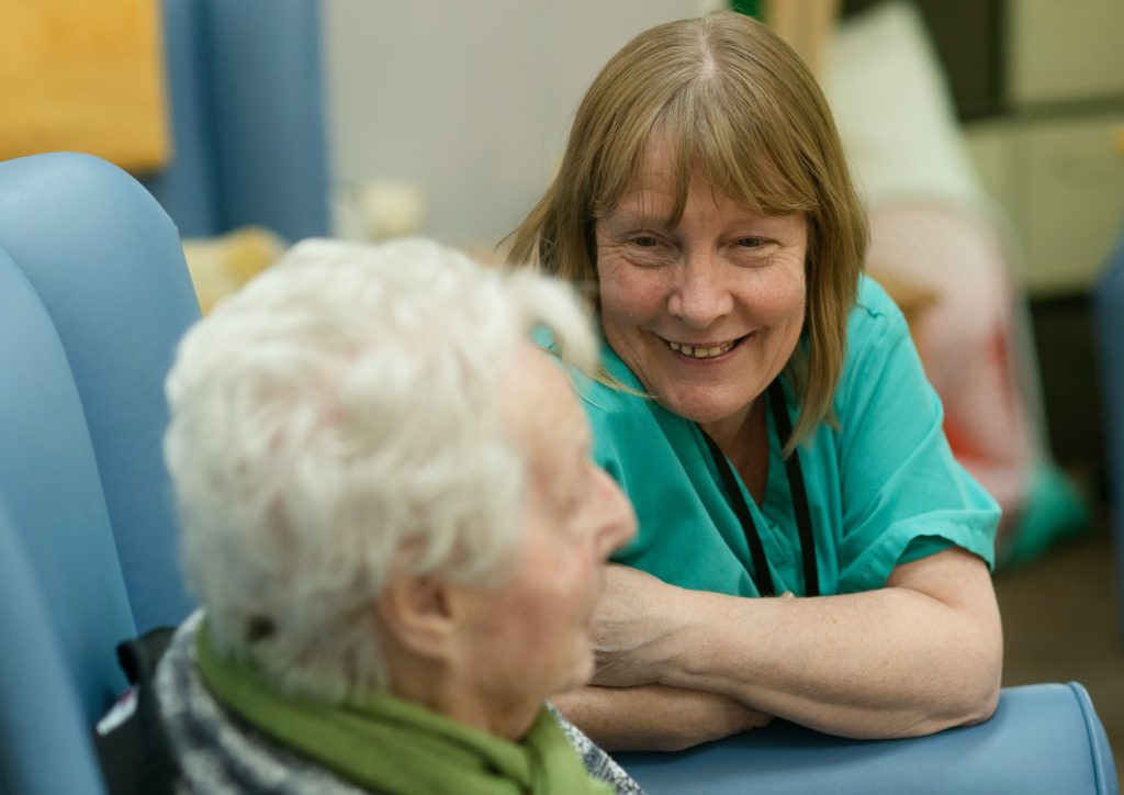 a senior being supported by staff member in teal