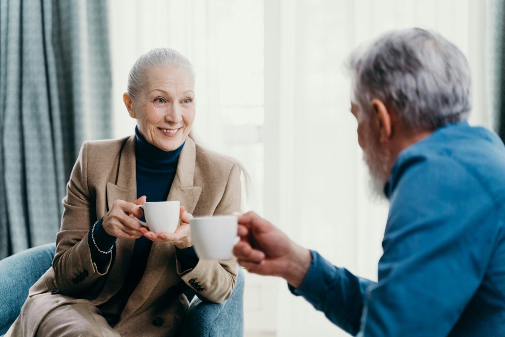 seniors having conversation over coffee together smiling